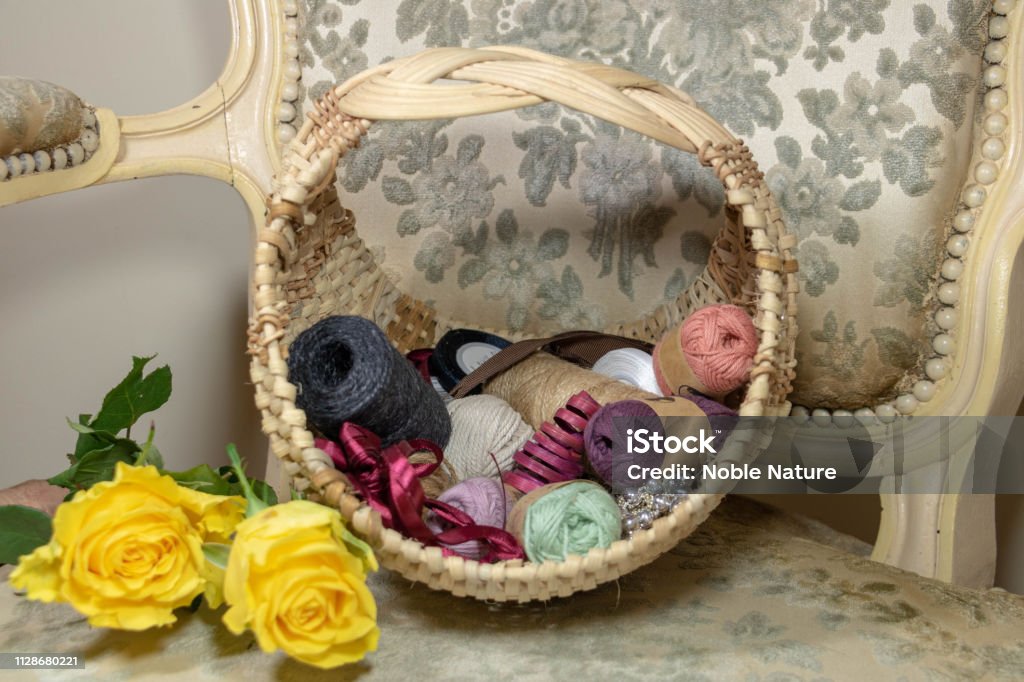Female boudoir, Josephina-shaped wicker basket for needle and yellow rose work on ancient shepherdess Wicker basket, Josephina basketry from the beginning of the 20th century, special basketry for needlework. Very feminine Sewing Class Stock Photo