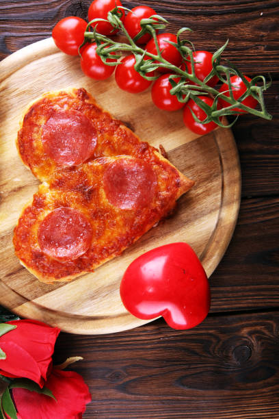 istock Valentines day pizza in heart shape on dark rustic wooden background. 1128681096