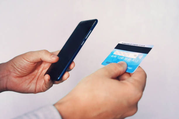 Online payment concept. Man using credit card with mobile phone at white background. Male hands holding smartphone with blank screen and reverse bank card. Person pays using mobile. Transaction. Online payment concept. Man using credit card with mobile phone at white background. Male hands holding smartphone with blank screen and reverse bank card. Person pays using mobile. Transaction cvc stock pictures, royalty-free photos & images