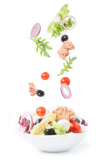 Tuna salad ingredients: baby cos lettuce head, cherry tomatoes, egg ,sweet onion cross section and open tuna can isolated on white