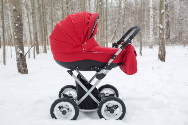 Classic red baby stroller with large wheels and a cradle. Walk in the winter forest with a baby in a pram. baby stroller winter stock pictures, royalty-free photos & images