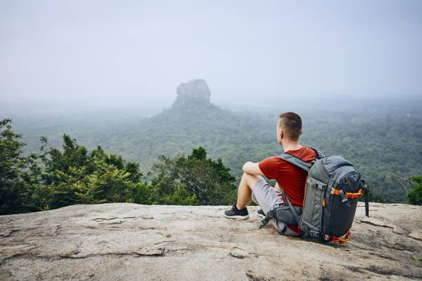 Sigiriya rock formation Young man with backpack against Sigiriya Rock (UNESCO World Heritage Site). View from Pidurangala Rock in Sri Lanka. dambulla stock pictures, royalty-free photos & images
