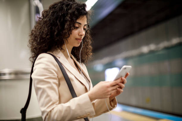 молодая женщина с помощью смартфона на станции метро - rush hour audio стоковые фото и изображения