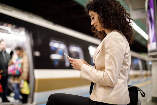 istock Young businesswoman using mobile phone while waiting for the train on the subway station 1128684072