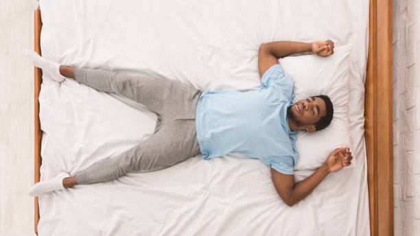 Young african-american man sleeping in bed top view Bedtime. Black millennial guy sleeping, lying on back in bed, top view man sleeping top view stock pictures, royalty-free photos & images