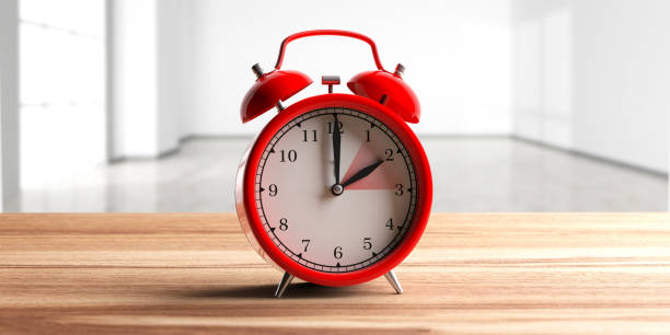 istock European daylight saving time. Red alarm clock on wooden desk, empty home background. 3d illustration 1128684830