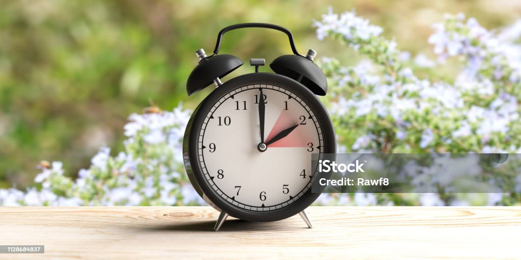 Horario europeo. Reloj despertador de escritorio de madera, desenfoque fondo de naturaleza de primavera. Ilustración 3D - Foto de stock de Adelantar una hora en primavera - Frase corta libre de derechos
