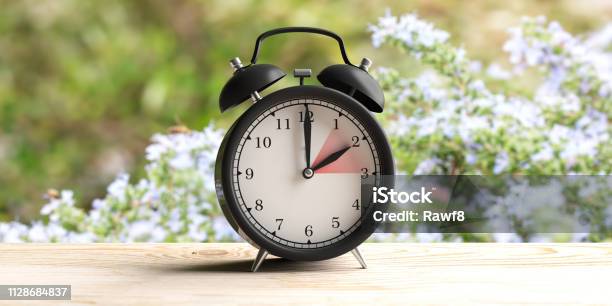 European Daylight Saving Time Alarm Clock On Wooden Desk Blur Spring Nature Background 3d Illustration Stock Photo - Download Image Now