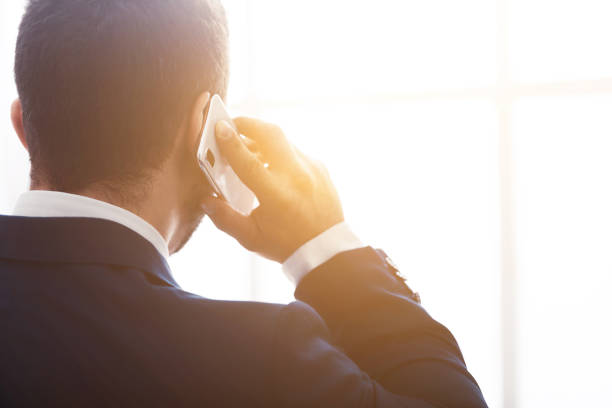 Businessman talking on phone, consulting clients, back view