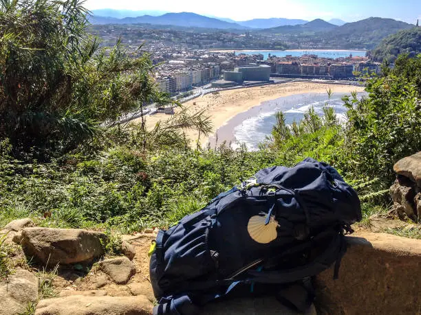 San Sebastian, Basque Country, Spain â September, 2018: A pilgrims backpack on a hill with an amazing view over San Sebastian, Camino del Norte or the Northern Way, route along Northern coast of Spain