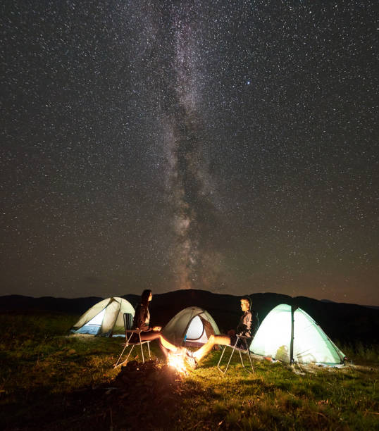 istock Couple tourists at night camp in mountains under starry sky 1128694472