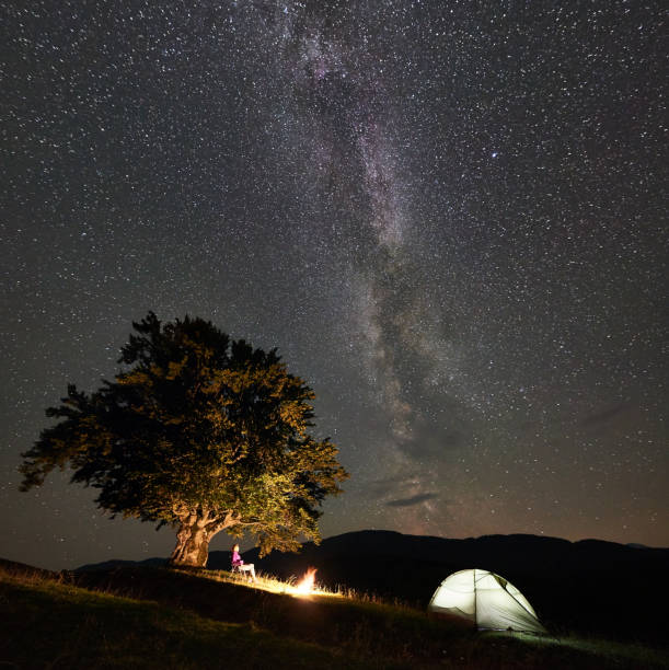 istock Woman resting at night camping in mountains under starry sky 1128694485