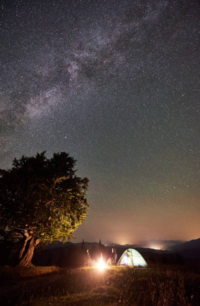 istock Couple tourists at night camp in mountains under starry sky 1128694496