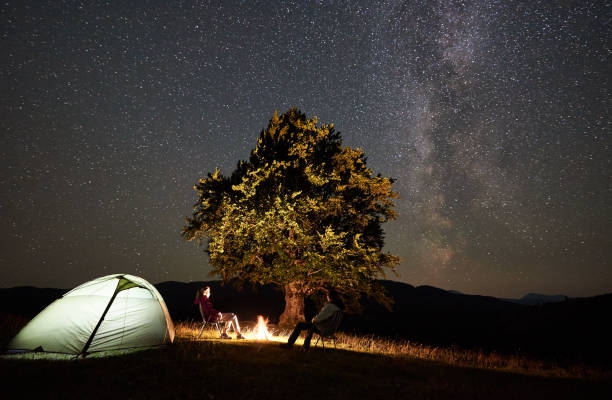 istock Couple tourists at night camp in mountains under starry sky 1128694502