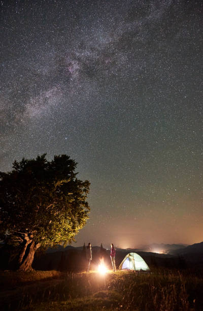 istock Couple tourists at night camp in mountains under starry sky 1128694505