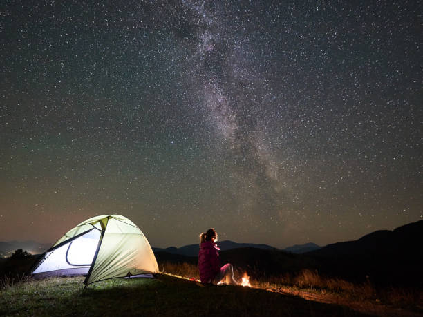 istock Woman resting at night camping in mountains under starry sky 1128694512