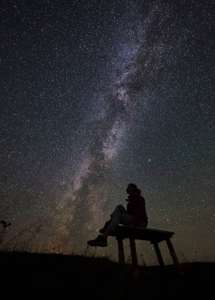 istock Woman resting at night camping in mountains under starry sky 1128694514