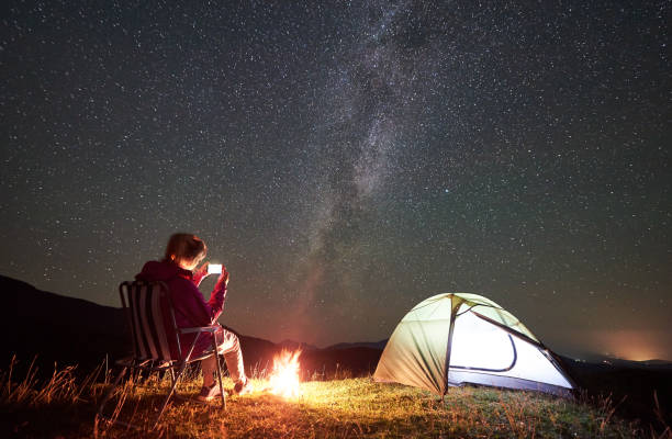 istock Woman resting at night camping in mountains under starry sky 1128694515