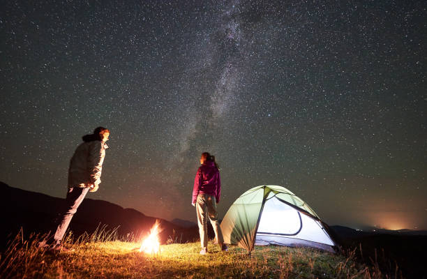 istock Couple tourists at night camp in mountains under starry sky 1128694516