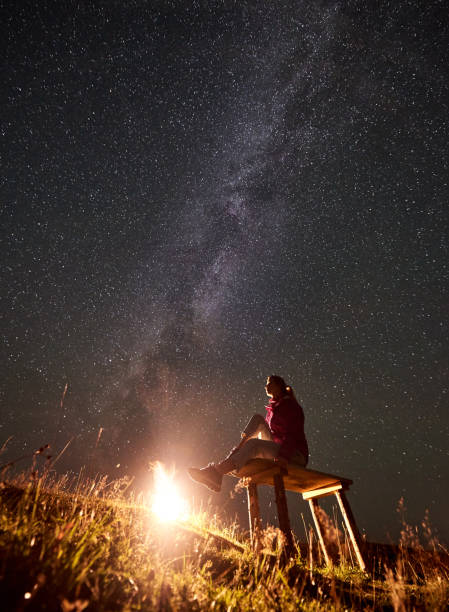 istock Woman resting at night camping in mountains under starry sky 1128694519