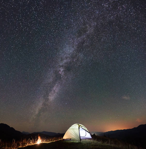 istock Tourist camping at night in the mountains under starry sky 1128694521