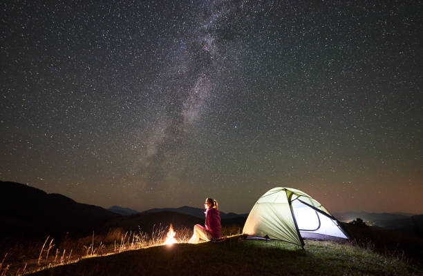 istock Woman resting at night camping in mountains under starry sky 1128694522