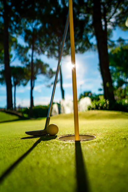 istock Mini Golf yellow ball with a bat near the hole at sunset 1128694816
