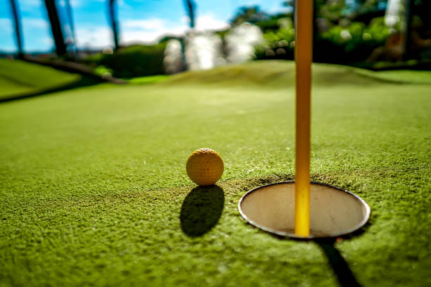 istock Mini Golf yellow ball on green grass at sunset 1128694822