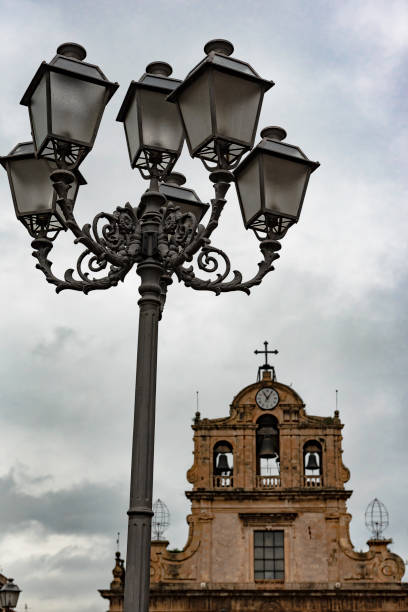 Street lamp against the background of a cloudy sky and a fragment of building