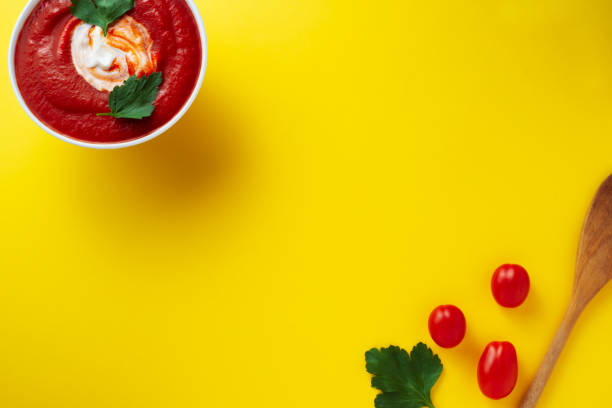 tamato soup with cherry tomatoes parsley over yellow background with copy space, flat lay stock photo