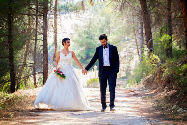 istock Wedding couple walking between trees in forest. 1128697426