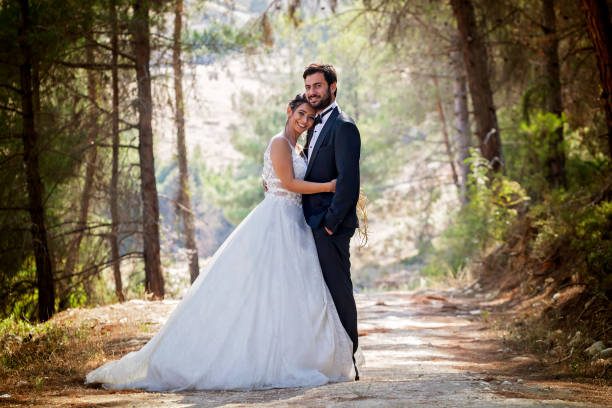 Wedding couple walking between trees in forest. Wedding couple walking between trees in forest. wedding dress photos stock pictures, royalty-free photos & images