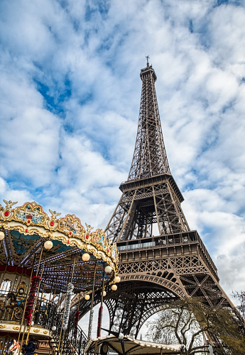 Paris, France, January 3, 2019: Eiffel tower in winter with carousel in foreground, against dramatic sky - Paris, France