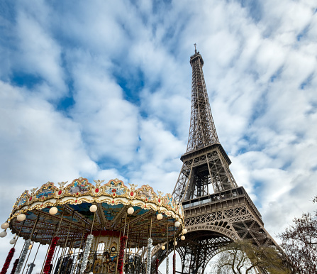 Paris, France, January 3, 2019: Eiffel tower in winter with carousel in foreground, against dramatic sky - Paris, France