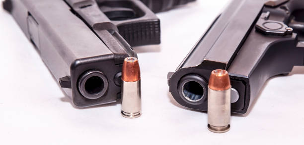 istock Two black pistols, a 9mm and a 40 caliber each with a bullet to it on front of the muzzle 1128702365