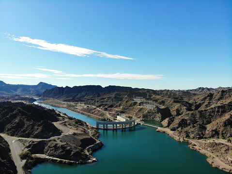 Aerial view of Parker Dam and hydroelectric equipment on the border between Arizona and California. The dam backs up the Colorado River which flows to the south and forms Lake Havasu to the north.