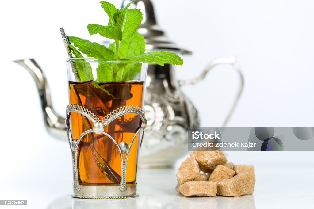 Traditional arabic mint tea in the typical glass Traditional refreshing Arabic mint tea. Isolated on the white background. Tea - Hot Drink Stock Photo