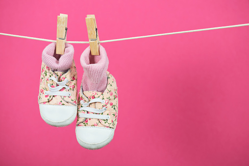 Pink hanging baby shoes on clothesline.