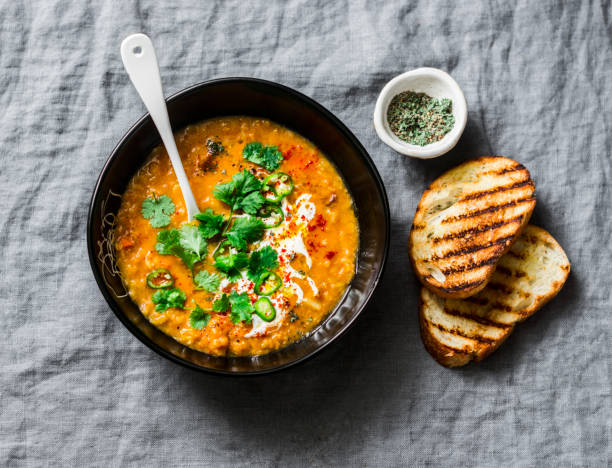 istock Pureed yellow peas and tomatoes vegetarian soup on grey background, top view 1128708713
