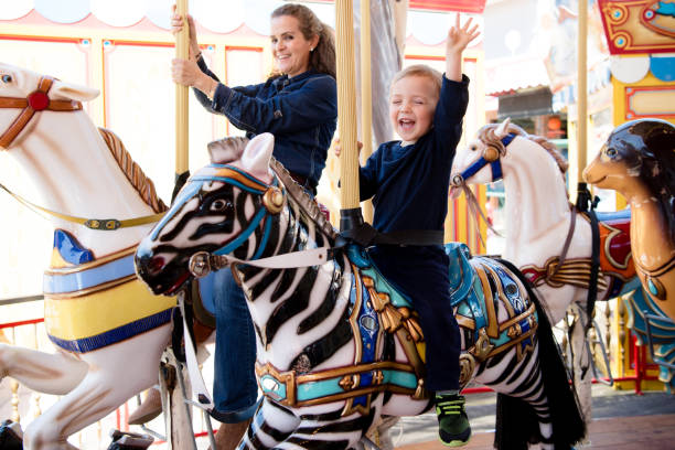 istock Happy boy and mother riding on carousel 1128709187