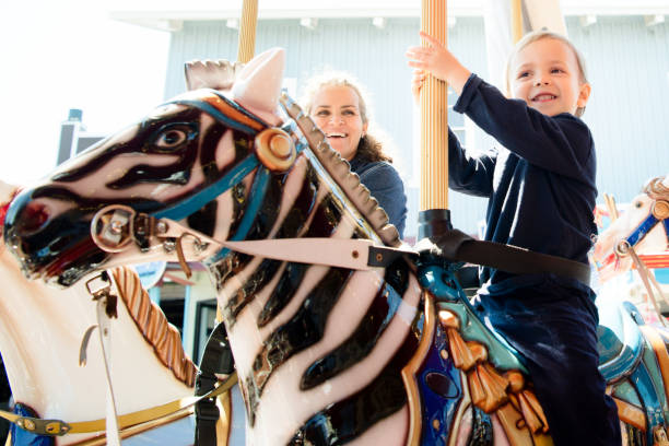 istock Happy boy and mother riding on carousel 1128709507