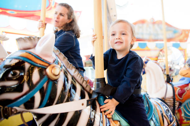 istock Happy boy and mother riding on carousel 1128709527