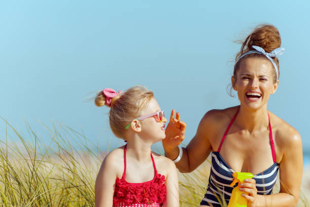 istock smiling modern mother and child on beach applying SPF 1128710842