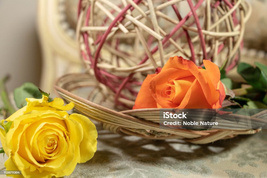 Set flowers and basketry for a feminine and natural decoration Wicker top, wicker ball and 2 colorful roses Armchair Stock Photo