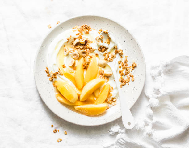 istock Greek yogurt with caramelized quince, granola, hazelnut on light background, top view. Delicious breakfast, dessert. Copy space 1128711584