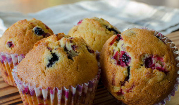 istock Muffins with red and black currant. paper bakeware with Valentine's day design with pink hearts. Close up, side view 1128715844