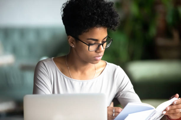 istock Concentrated african beautiful woman studying reading a book 1128717598