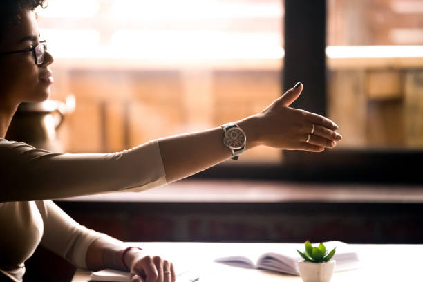 istock Female sitting at table holds out her hand for handshake 1128717615