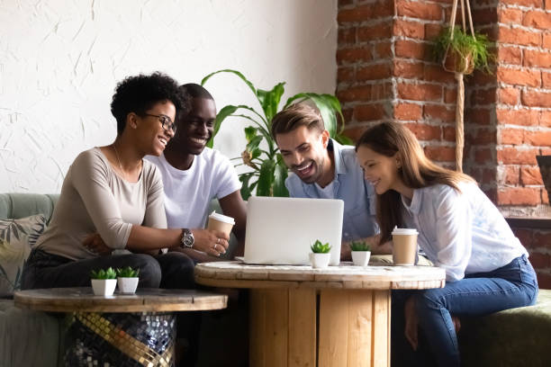 istock Diverse friends sitting in cafe watching funny videos using computer 1128717630
