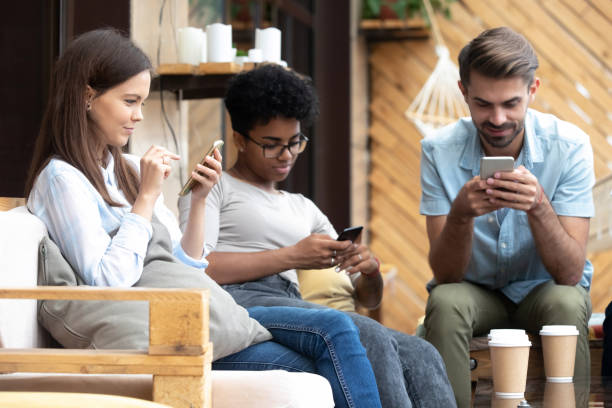 jóvenes sentados juntos en café, navegar por internet a través de los teléfonos - african descent addiction african ethnicity rudeness fotografías e imágenes de stock